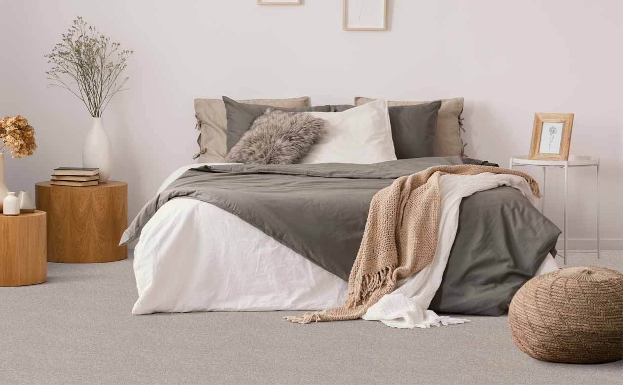 Bedroom with bed, wood side tables and gray carpet