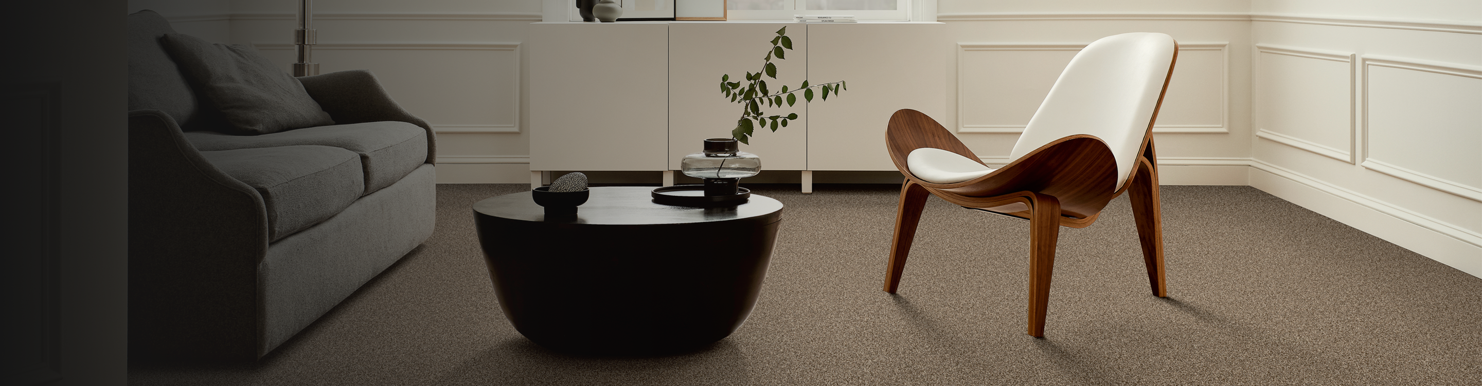 Sitting area with a wood accent chair, black coffee table and brown carpet